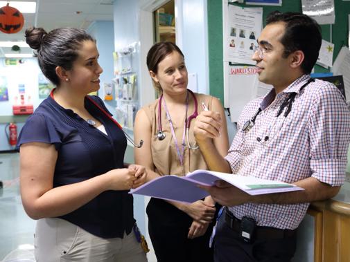 Three doctors in discussion on ward.